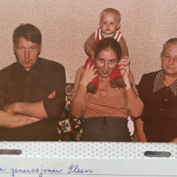 Familiebilde med fire personar i sofa. Ung kvinne i midten med baby på skuldrane, mann til venstre, eldre kvinne til høgre. Fotografert i 1980.